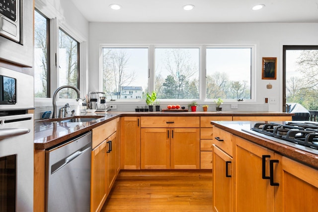 kitchen featuring dishwasher, a sink, light wood-style floors, gas stovetop, and recessed lighting