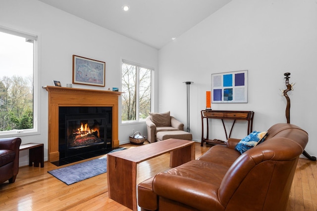 living room featuring light wood-style floors, healthy amount of natural light, a fireplace with flush hearth, baseboards, and recessed lighting
