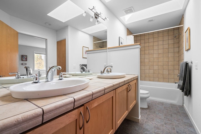 bathroom featuring a skylight, toilet, bathing tub / shower combination, and double vanity