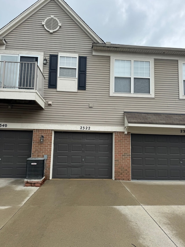 2322 Arcadia Dr, Canton, MI 48188 - townhome / multi-family property featuring brick siding, a balcony, an attached garage, central AC unit, and driveway