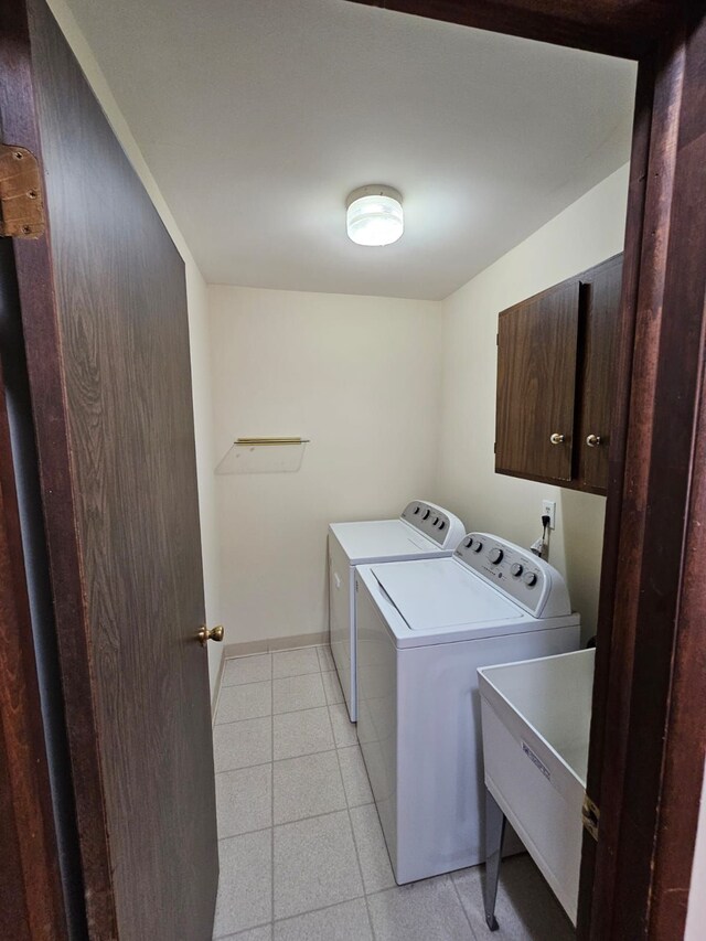 laundry room with cabinet space, washer and clothes dryer, and light tile patterned floors