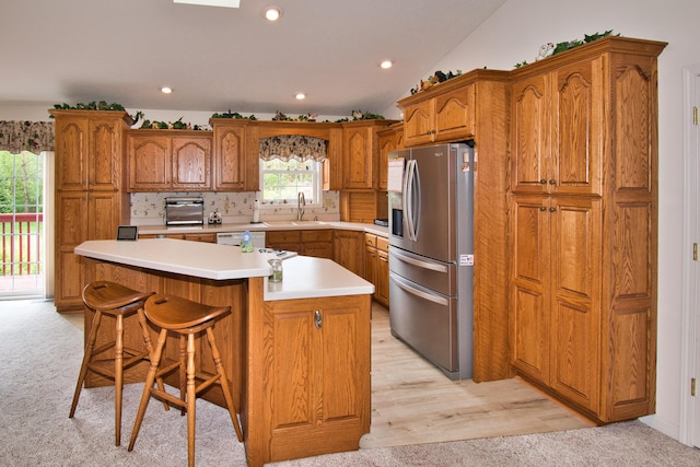 2688 White St, Niles, MI 49120 - kitchen featuring stainless steel fridge with ice dispenser, brown cabinets, vaulted ceiling, light carpet, and a breakfast bar area