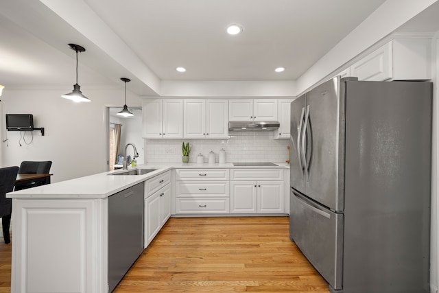kitchen with appliances with stainless steel finishes, a sink, light wood-type flooring, a peninsula, and under cabinet range hood