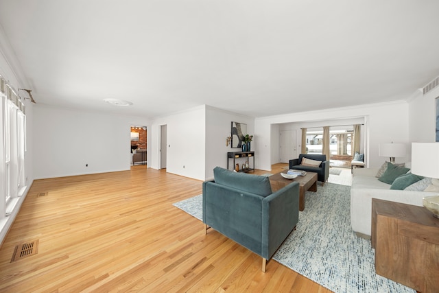 living room with light wood-style flooring, crown molding, and baseboards