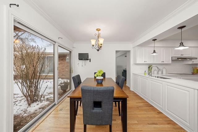 dining room featuring a chandelier, crown molding, and light wood finished floors