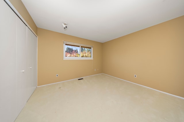 unfurnished bedroom featuring a closet, light carpet, and baseboards