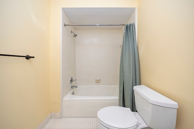 bathroom with toilet, shower / bath combination with curtain, tile patterned floors, and baseboards