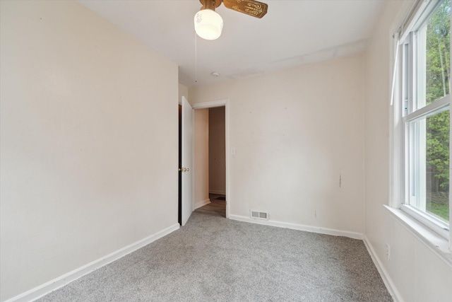 carpeted spare room featuring baseboards and ceiling fan