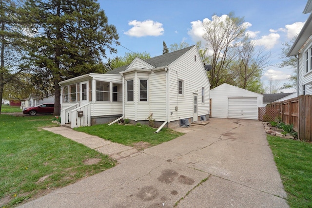 view of front of house featuring an outdoor structure, a sunroom, driveway, a garage, and roof with shingles