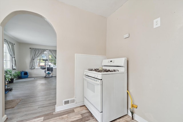 kitchen featuring white gas stove, arched walkways, and light wood-type flooring