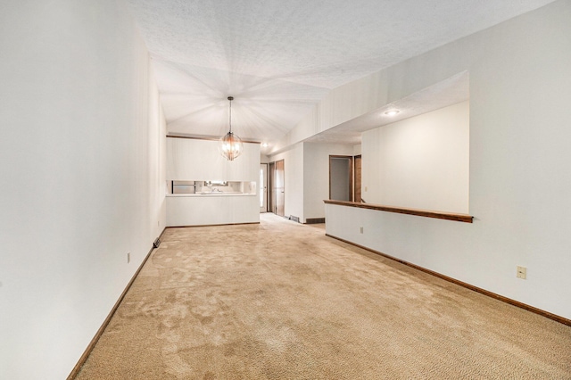 3217 Westminster Dr SE Unit 69, Grand Rapids, MI 49512 - unfurnished living room featuring a chandelier, carpet floors, baseboards, lofted ceiling, and a textured ceiling