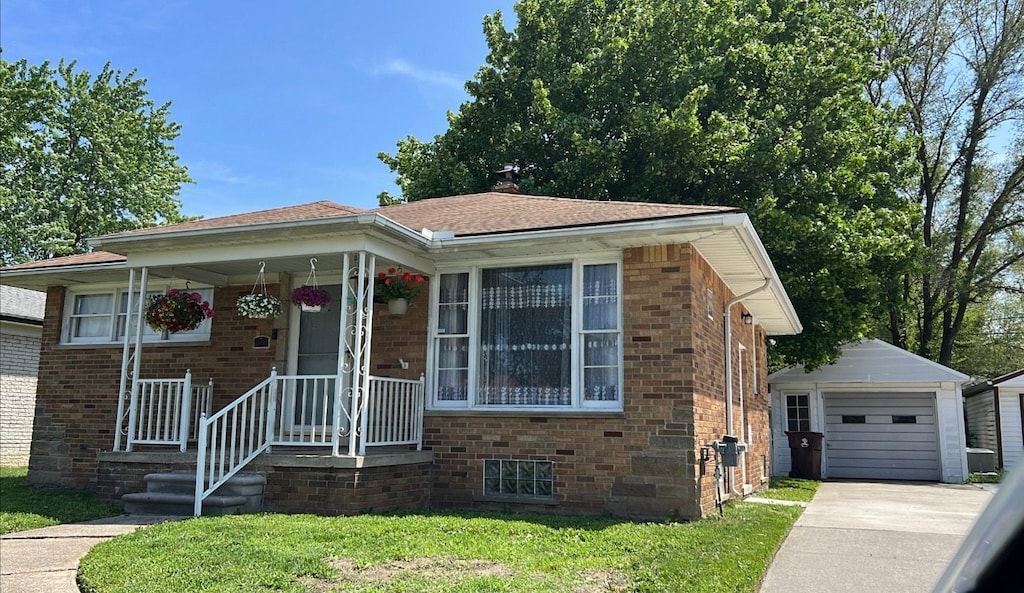 view of front of house featuring brick siding, an outdoor structure, driveway, a detached garage, and a front lawn