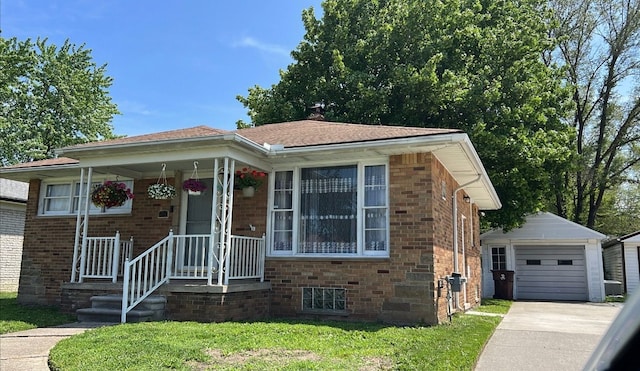 view of front of house featuring brick siding, an outdoor structure, driveway, a detached garage, and a front lawn