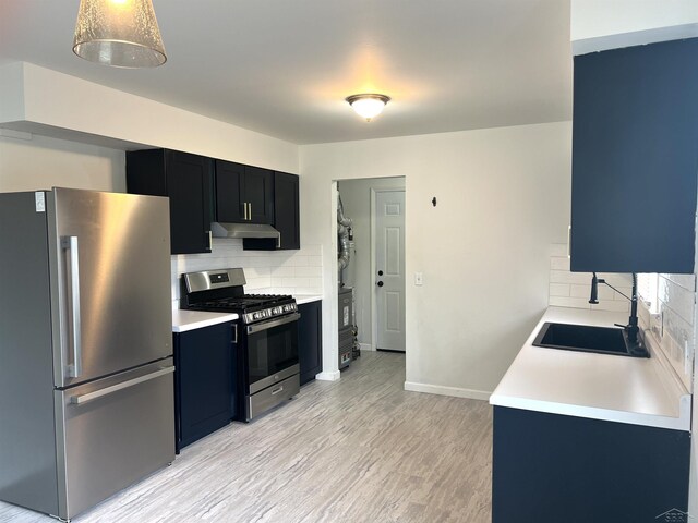 kitchen featuring stainless steel appliances, under cabinet range hood, backsplash, and light countertops