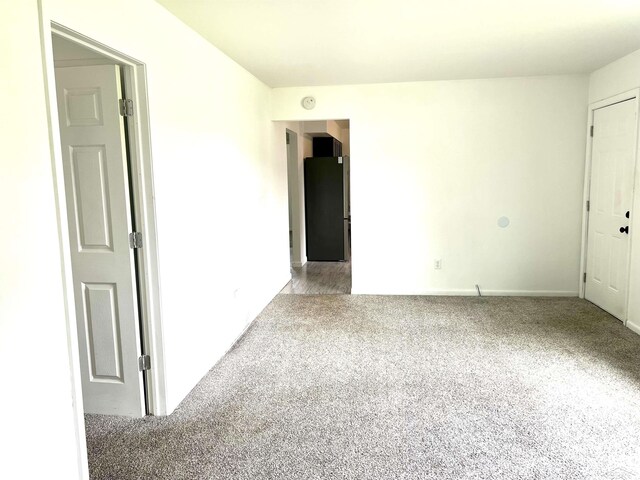empty room featuring light carpet and baseboards
