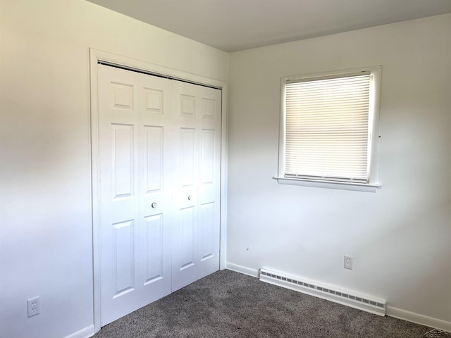 unfurnished bedroom featuring a baseboard radiator, carpet floors, a closet, and baseboards