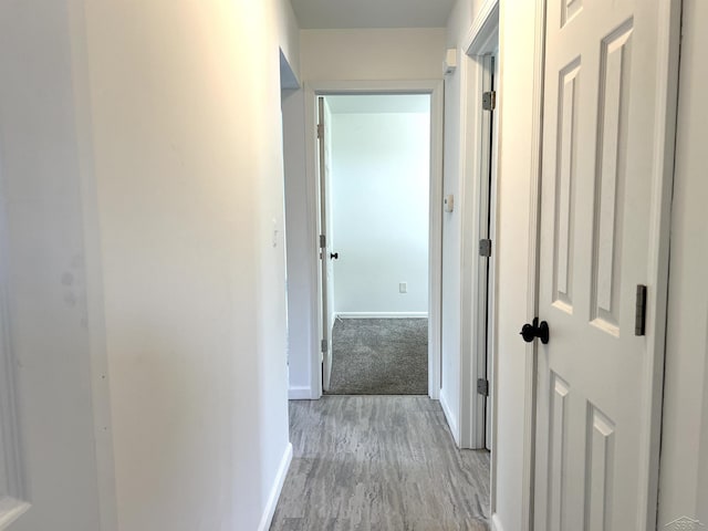 corridor with baseboards and light wood-style floors