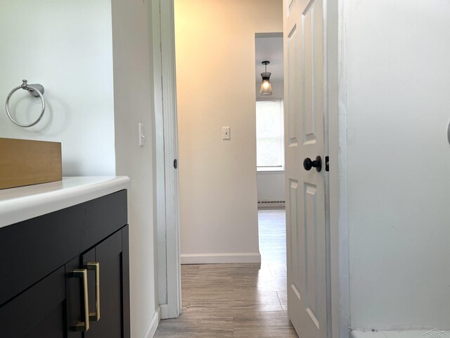 hallway featuring light wood-style flooring and baseboards