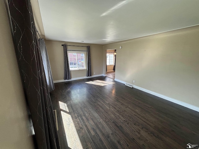 unfurnished living room featuring baseboards and dark wood-type flooring