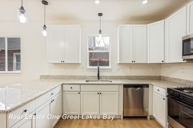 kitchen featuring stainless steel appliances, a sink, a peninsula, white cabinetry, and recessed lighting