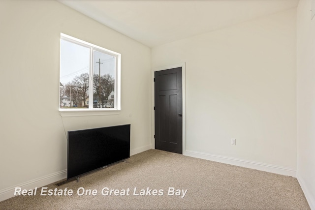 unfurnished room with carpet flooring and baseboards