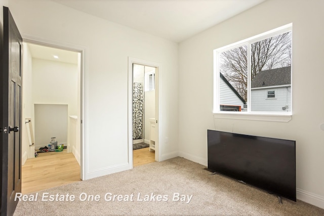 unfurnished bedroom featuring carpet flooring, baseboards, and ensuite bath