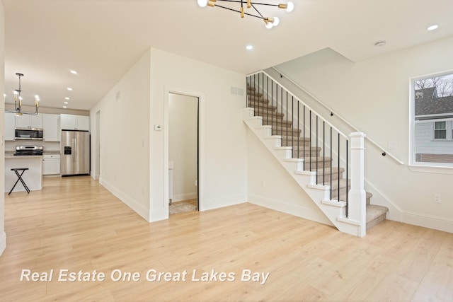 staircase featuring a chandelier, wood finished floors, baseboards, and recessed lighting
