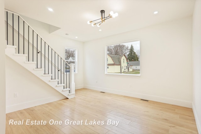 unfurnished room featuring a chandelier, baseboards, stairway, recessed lighting, and wood finished floors