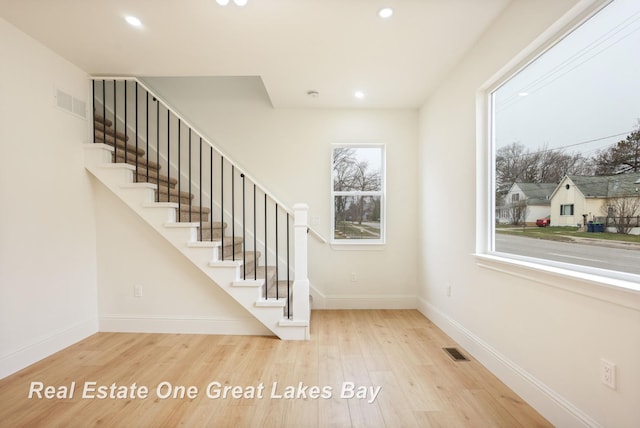 staircase featuring wood finished floors, baseboards, and recessed lighting