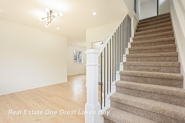 stairway with wood finished floors, baseboards, recessed lighting, and a chandelier