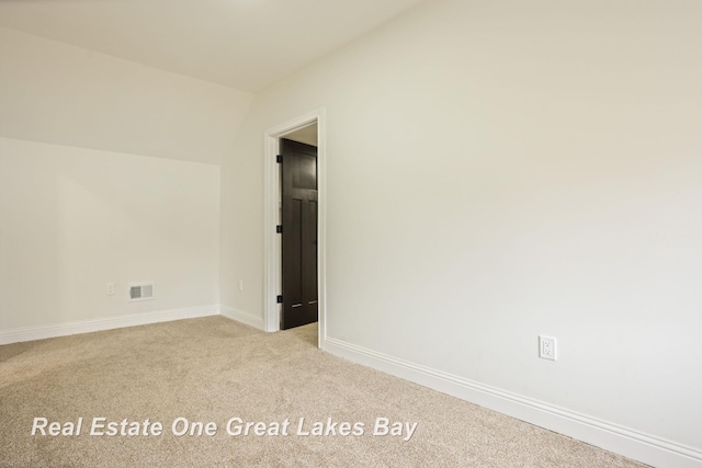 spare room featuring carpet, baseboards, and lofted ceiling