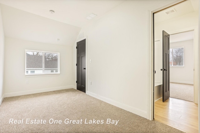 unfurnished bedroom with carpet flooring, baseboards, and lofted ceiling
