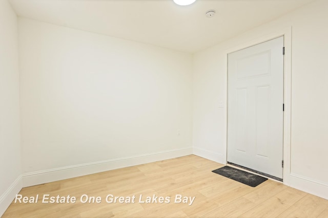 unfurnished room featuring light wood-style floors, a smoke detector, and baseboards