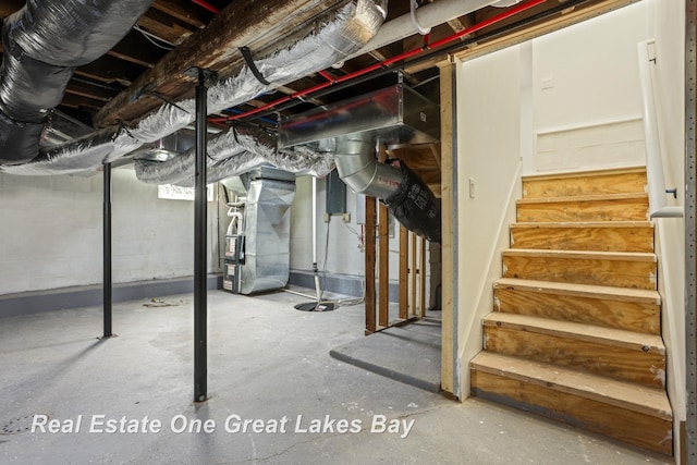unfinished basement featuring heating unit and stairway