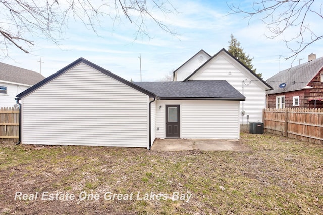 rear view of house with fence, central air condition unit, and roof with shingles