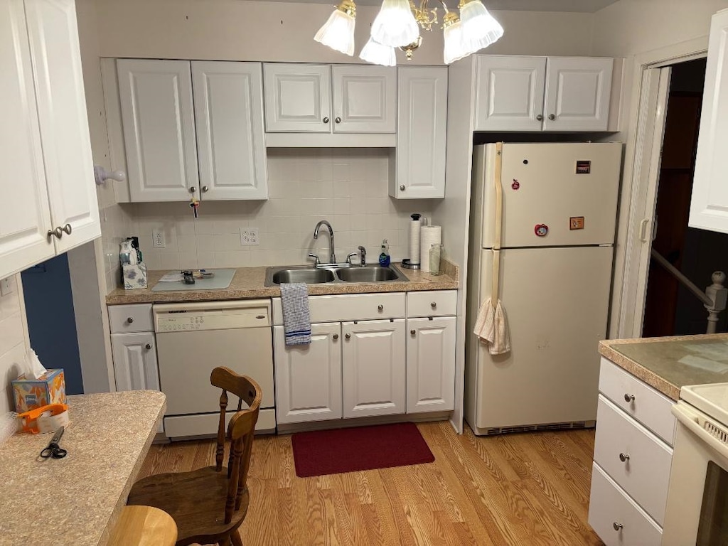 kitchen with white appliances, a sink, white cabinetry, backsplash, and light wood finished floors