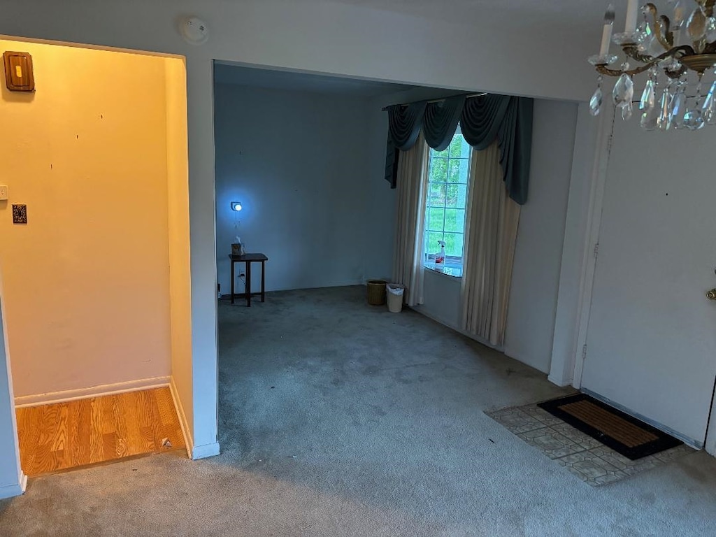 carpeted spare room featuring a chandelier and a smoke detector