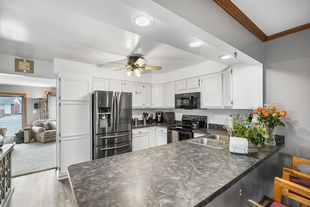 kitchen with black appliances, a peninsula, a sink, a ceiling fan, and ornamental molding