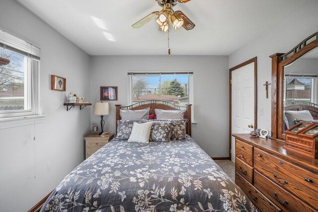 carpeted bedroom featuring multiple windows, ceiling fan, and baseboards