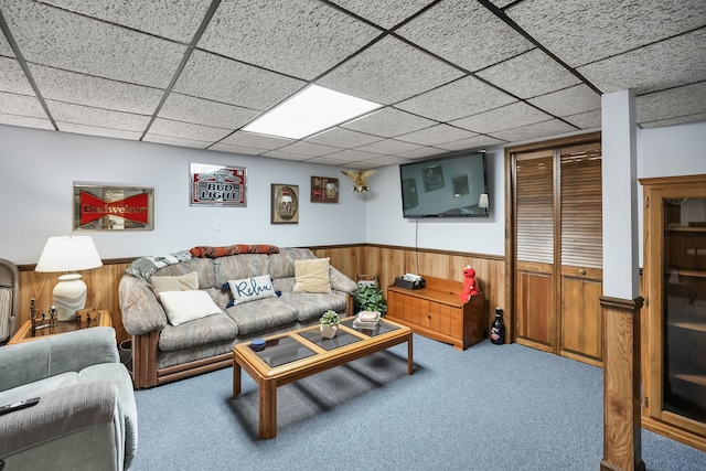 carpeted living room with a wainscoted wall, wooden walls, and a paneled ceiling