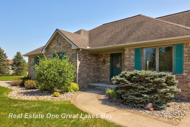 view of front of property with brick siding and roof with shingles