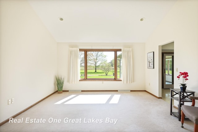 carpeted spare room with lofted ceiling and baseboards