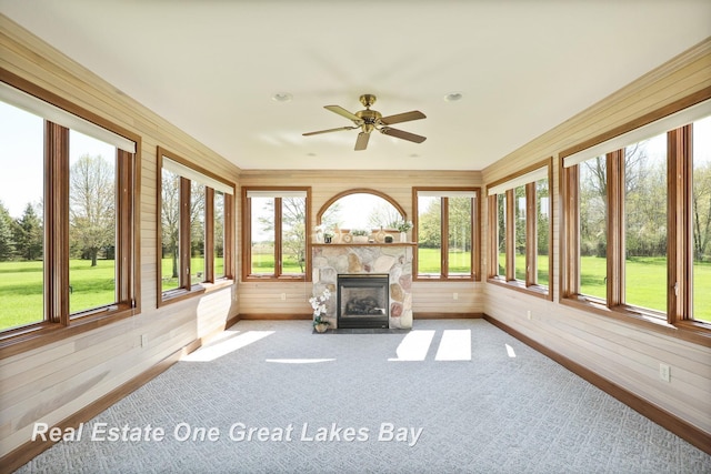unfurnished sunroom featuring wooden walls, baseboards, and carpet flooring