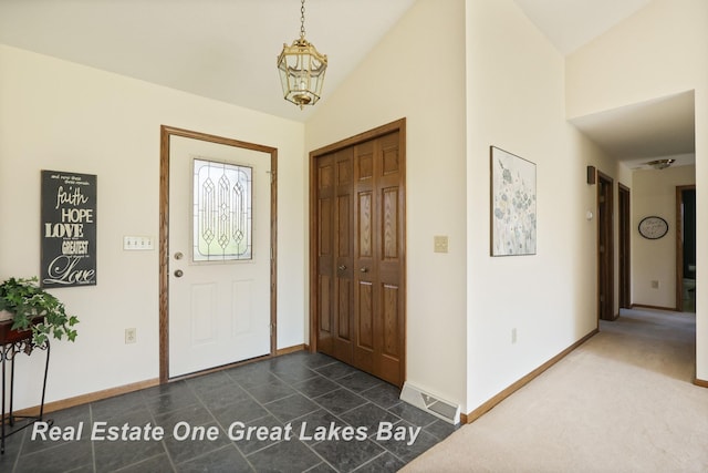 foyer entrance featuring baseboards and vaulted ceiling
