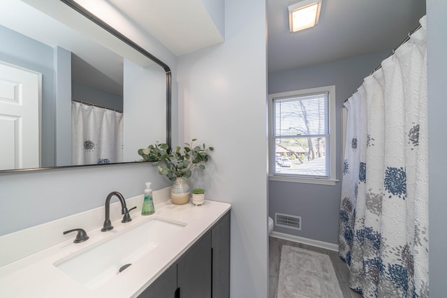bathroom with toilet, baseboards, and vanity