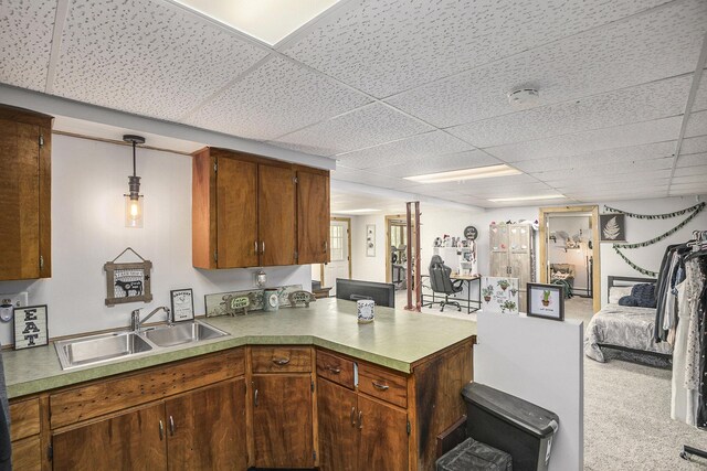 2660 Barber Rd, Grass Lake, MI 49240 - kitchen featuring a sink, a peninsula, a paneled ceiling, light countertops, and brown cabinets