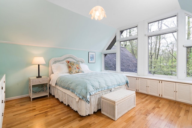 bedroom featuring vaulted ceiling, light wood-style flooring, and baseboards