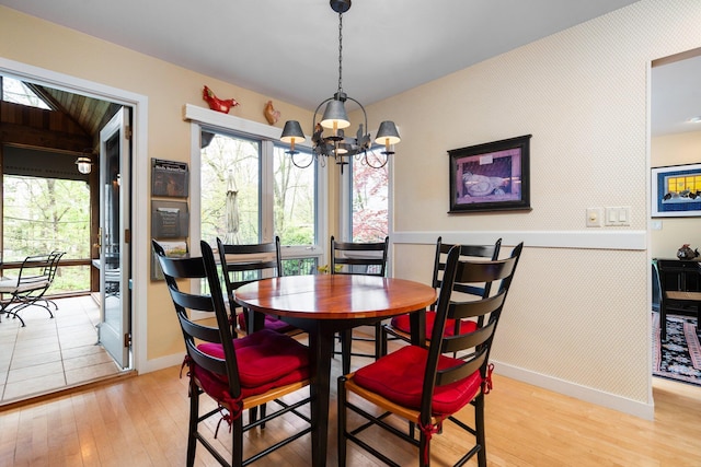 dining space with a chandelier, baseboards, wallpapered walls, light wood finished floors, and plenty of natural light