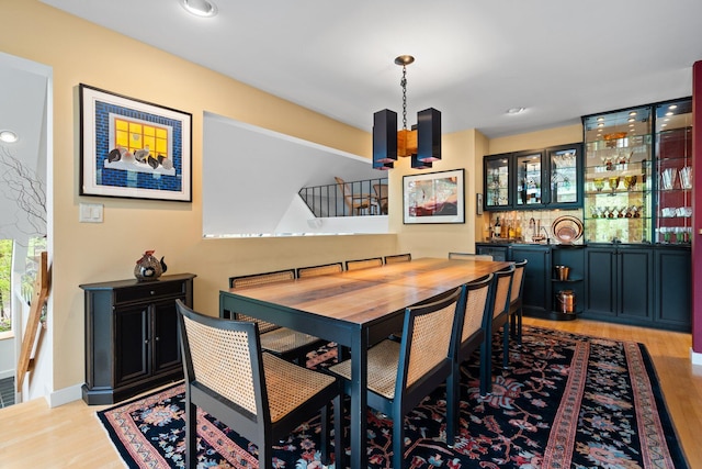 dining room featuring light wood finished floors, bar, and a chandelier