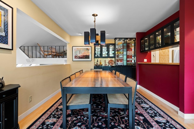 dining room featuring wood finished floors, a chandelier, and baseboards